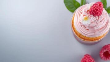 Cupcake with pink frosting and raspberries on a gray background photo