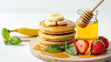Stack of pancakes with honey, banana and strawberries photo