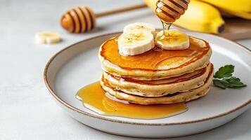 A stack of pancakes with honey and bananas photo