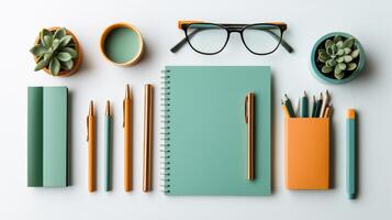 A desk with a notebook, pencils, pens, and a plant on a white surface photo