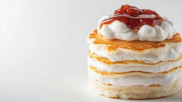 A stack of pancakes topped with whipped cream and jam photo