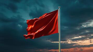 Red flag waving in the wind against a cloudy sky photo