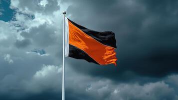 An orange and black flag flies in the wind photo