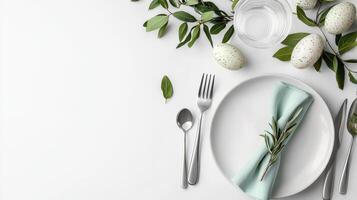 Easter table setting with white tablecloth, silverware, and green leaves photo