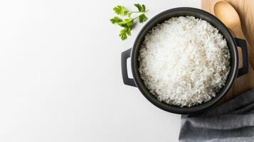 Top view of a bowl of white rice on a white table with wooden spoon and herbs photo