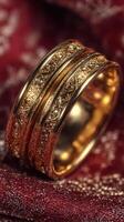 Elegant gold ring with intricate design on a textured red fabric backdrop photo