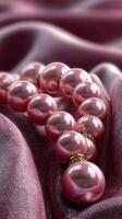 Elegant pink pearl necklace draped on luxurious fabric with soft sheen in a warm light setting photo