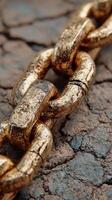 Close-up view of a golden chain resting on a cracked surface highlighting its textured detail photo