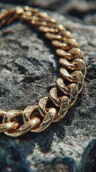 Gold chain jewelry displayed on a textured rock surface during daylight showcasing intricate links and craftsmanship photo