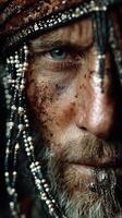 Weathered pirate close-up with intricate beaded adornments and intense gaze under dramatic lighting photo