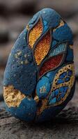 Artistic rock featuring vibrant blue, gold, and intricate patterns mentioned in the creative display in a natural setting photo