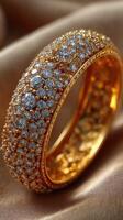 Sparkling golden ring adorned with numerous diamonds rests elegantly on soft fabric photo