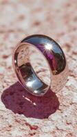Shiny silver ring resting on textured surface during bright daylight photo