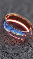 Unique reflective wedding ring rests on textured surface during bright daylight showcasing natural scenery photo