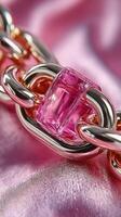 Close-up of an elegant metallic chain with a transparent pink link on a lustrous surface photo