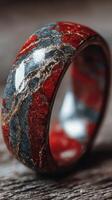 Unique stone ring with vibrant red and blue patterns showcased on wooden surface photo