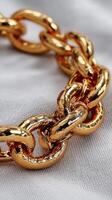 Shiny golden chain links on soft fabric highlighting intricate design and craftsmanship during daylight hours photo