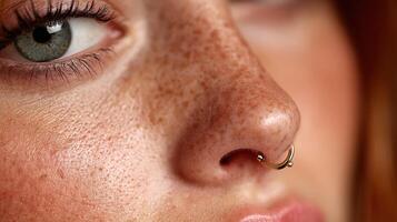 Portrait of a young woman with freckles and a septum piercing showcasing natural beauty in warm lighting photo