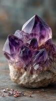 Beautiful cluster of amethyst crystals displayed on a textured surface with small crystals nearby in soft lighting photo