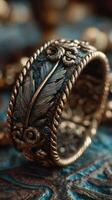 Ornate bronze ring with intricate feather and floral design on textured surface, showcasing craftsmanship and artistry photo