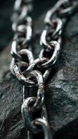 Close-up view of an old metallic chain resting on textured stone surface in natural lighting photo