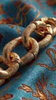 Golden decorative chain laid on a vibrant blue fabric with intricate patterns, showcasing craftsmanship and elegance in design photo