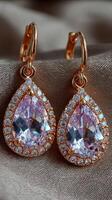 Elegant rose gold earrings with pear-shaped gemstones and sparkling accents displayed on a soft fabric background photo