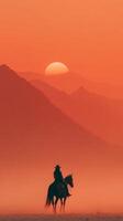 Cowboy silhouette riding horse against sunset in a misty mountain landscape near the horizon photo