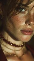 Close-up portrait of a young woman with freckles and striking blue eyes wearing layered necklaces at dusk photo