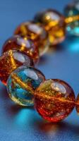 Vibrant glass beads in amber and teal colors are displayed on a smooth surface showcasing intricate details and reflections photo