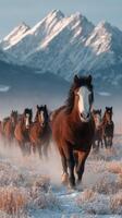 Majestic horses galloping through snow-covered landscape with mountains in the background during golden hour photo