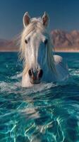 Majestic white horse swimming in crystal clear waters against a stunning mountainous backdrop photo