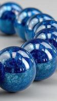 Bright blue decorative spheres displayed in a row on a smooth surface with elegant reflections and unique textures photo