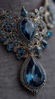 Intricate gold necklace adorned with stunning blue gemstones displayed on a textured surface photo