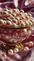 Elegant display of pink pearls in a glass bowl resting on silky fabric in soft natural light photo