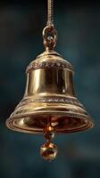 Elegant brass bell hanging from a rope against a blurred blue background, showcasing intricate designs and craftsmanship photo