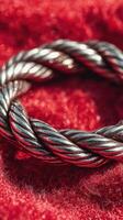 Intricately woven silver ring resting on a vibrant red fabric background showcasing detailed craftsmanship photo