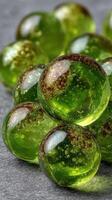 Colorful green glass orbs with air bubbles arranged in a decorative pattern on a textured surface photo
