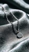 Silver necklace resting on satin fabric showcases elegance and simplicity with a circular pendant photo