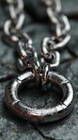 Close-up of a metallic chain link resting on a textured stone surface highlighting its polished finish and intricate design photo