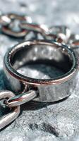 Close-up of a metallic chain link with a circular ring on a textured surface in natural light photo