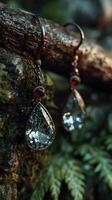 Elegant teardrop earrings displayed against a natural, mossy background with soft lighting photo