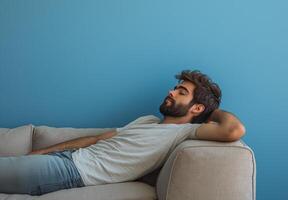 A man is laying on a couch with his head resting on his arm photo