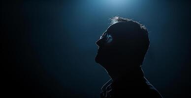 A man with glasses is standing in a dark room photo