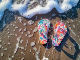 Two colourful flip flops are on the beach, with the ocean in the background photo