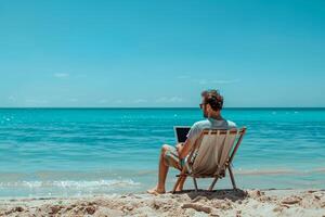 A man is sitting on a beach chair with a laptop in front of him photo