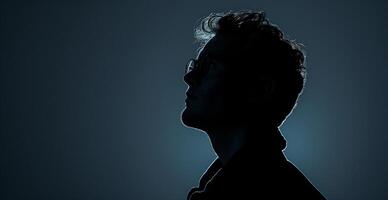 A Silhouette Of Thought, A Man In Contemplation Against A Deep Blue Background photo