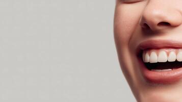Close up of a smiling woman mouth showing white teeth and natural lips on a light background photo