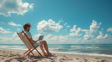 A man is sitting on a beach chair with a laptop in front of him and beautiful sky photo