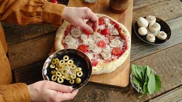 Making pizza. Woman preparing homemade pizza and putting olives on dough video
